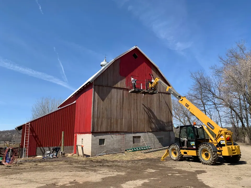 Cedar Tone painters on a lift spraying a tall barn red in Greenfield