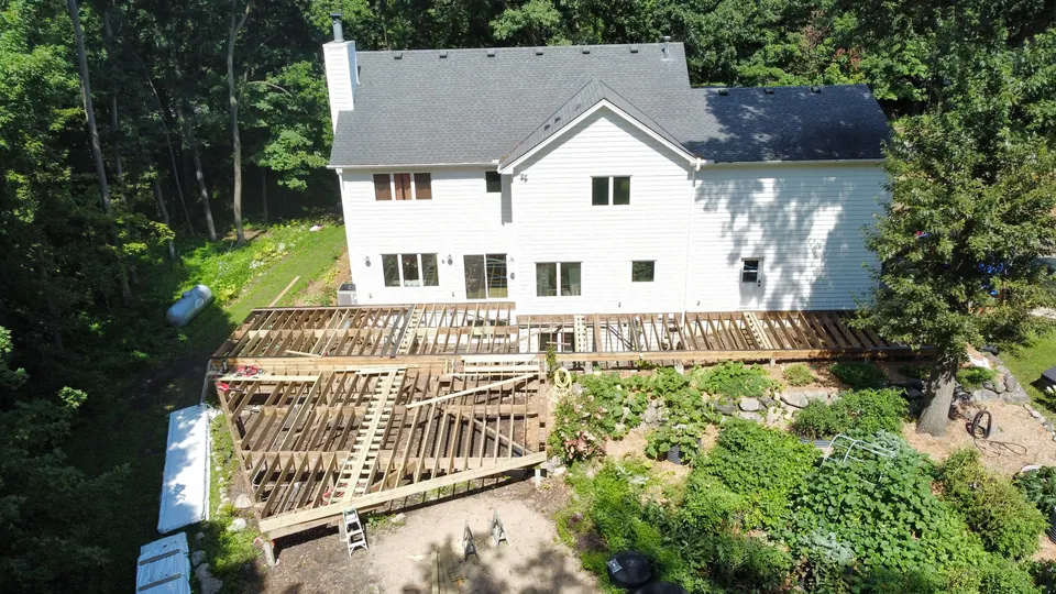 Aerial view of a white two-story home with new deck framing in progress