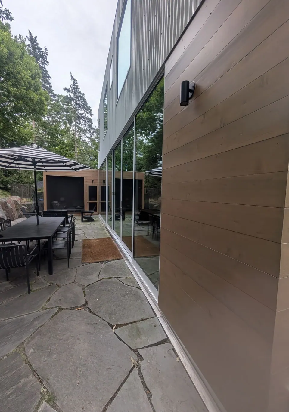 Stained wood siding beside tall glass doors on the patio